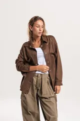 Sobrecamisa oversize de efecto gamuza en color marrón, con cierre frontal de botones metálicos, cuello clásico y bolsillos frontales.