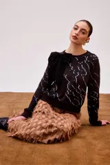 Buzo negro con estampado de líneas blancas y lazo decorativo en el hombro.