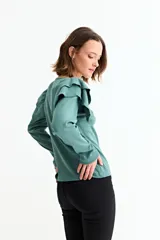 Remera de manga larga en color crudo, confeccionada en tejido acanalado, con detalle de volados en los hombros y cuello redondo.