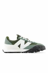 Championes New Balance modelo XC-72, con capellada de gamuza y nylon en tonos verde oliva y verde claro, logo "N" en blanco, entresuela blanca y suela de goma negra con diseño texturizado.