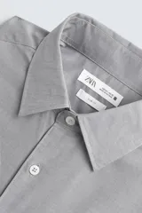 Camisa de corte slim fit confeccionada en tejido de algodón con textura. Presenta cuello italiano, manga larga con puños abotonados y cierre frontal de botones.