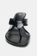 Sandalia de piel con acabado charol en color negro, diseño tipo thong con separación para el dedo, tacón fino medio y punta redonda.