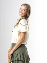 Blusa de algodón off white con cuello mao, botones frontales y mangas globo. Cuenta con canesú destacado con bordado floral en color azul marino.