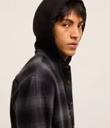Camisa masculina de franela a cuadros en tonos grises y negros, con capucha con cordón ajustable, cierre frontal abotonado y mangas largas.