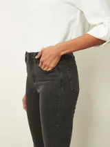 Jean de corte skinny en tono azul medio, con diseño de cinco bolsillos, cierre frontal con botón y cremallera, y costuras reforzadas.