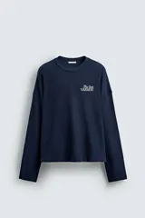 Sudadera boxy fit color azul marino, confeccionada en tejido rib, con cuello redondo y manga larga. Presenta un estampado blanco en el delantero con el texto "The Best Version".