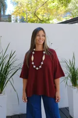 Sweater de punto color bordó, con cuello redondo, manga corta amplia y diseño holgado.