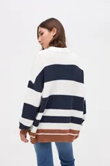 Buzo de punto con diseño de rayas horizontales en tonos bordó, azul marino y mostaza. Presenta cuello tipo polo con cartera de botones, mangas largas y calce holgado.