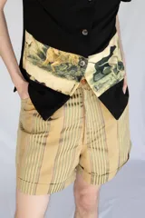 Short de vestir tiro alto color beige con rayas verticales en tonos verde oliva y marrón. Presenta un pliegue frontal (pinzas) y dobladillo en la botamanga.