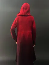 Tapado rojo con capucha, confeccionado en lana merino teñida con técnica tie-dye. Tiene corte recto, largo, bolsillos laterales y cierre cruzado con broches a presión ocultos.