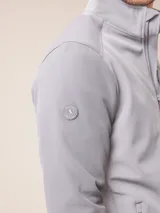 Campera softshell color gris, con cierre frontal completo, cuello alto y bolsillos laterales y en el pecho con cierre. Cuenta con logo bordado en el pecho y ajuste en los puños.