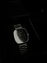 Reloj Casio Quartz con caja cuadrada plateada, esfera negra y correa de acero inoxidable plateada. Incluye fechador.