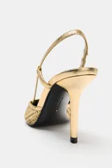 Zapato de tacón alto destalonado en color dorado con acabado metalizado y diseño de efecto trenzado. Presenta una tira trasera con elástico y puntera fina.