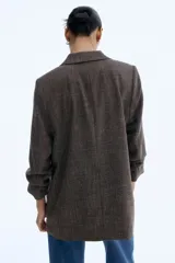 Blazer largo de botonadura sencilla con solapas de muesca, hombreras, pinzas en la cintura y bolsillos delanteros ribeteados. Presenta mangas tres cuartos con diseño remangado y forro interior.