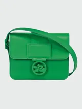 Bandolera Longchamp modelo Box-Trot S, color blanco con correa larga regulable. Presenta cierre con hebilla metálica con el logo de la marca.