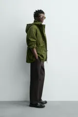 Parka técnica color verde militar de corte relaxed fit con cuello subido y capucha desmontable. Cuenta con bolsillos con solapa en el pecho y en la cadera, cintura ajustable con cordón y cierre frontal de cremallera oculta por solapa con botones a presión. Incluye un chaleco interior desmontable acolchado.
