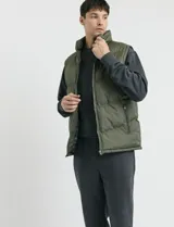 Chaleco capitoneado de color azul marino con cierre frontal completo y cuello alto. Presenta un diseño acolchado con costuras horizontales y forro interior con estampado escocés.