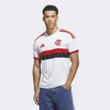 Camiseta de fútbol Adidas del CR Flamengo, modelo visitante 26. Diseño blanco con franjas horizontales roja y negra en el pecho, y detalles en rojo en los hombros. Incluye logo de Adidas y escudo del club bordados.