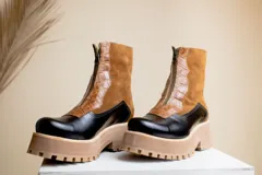 Botas cortas de cuero color marrón y negro con cierre frontal y suela track.