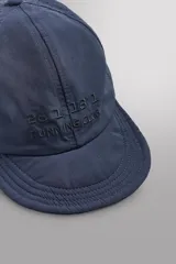 Gorra deportiva de tejido técnico ligero en color azul marino, con visera corta y paneles laterales perforados para mayor ventilación. Presenta logos bordados a tono en el frente.