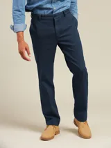 Pantalón de vestir color beige, de corte recto, con bolsillos laterales y traseros. Se ajusta a la cintura con cinturón de cuero marrón.