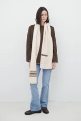 Buzo de tejido de punto color beige, con corte relajado, cuello redondo y mangas largas. Presenta detalles de terminaciones en color azul marino en los puños y en el ruedo inferior.