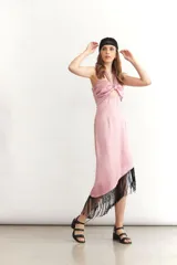 Vestido midi sin mangas color turquesa, con escote strapless y detalle de nudo frontal. El ruedo presenta un corte asimétrico con flecos negros largos.