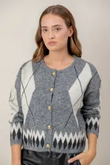 Cardigan de punto con diseño de rombos en tonos gris, blanco y negro. Presenta cuello redondo, cierre frontal con botones dorados y mangas largas.