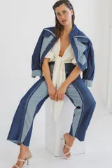 Jean de corte recto confeccionado en denim de algodón, con diseño bicolor que combina paneles en azul oscuro y azul claro. Presenta cierre frontal con cremallera y diseño de costuras verticales marcadas.