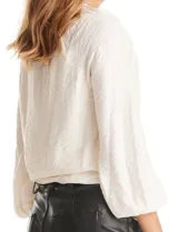 Blusa de satén color verde petróleo, con escote en V y cuello decorado con mostacillas bordadas. Presenta mangas largas con puños elásticos y ruedo también elastizado, brindando un ajuste cómodo y holgado.