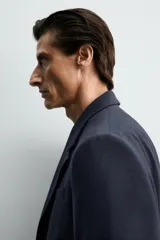 Blazer de corte regular confeccionado en lana de origen italiano. Presenta cuello con solapas de muesca, cierre frontal de un botón, bolsillos laterales con solapa y bolsillo de vivo en el pecho. Incluye abertura central en la espalda y forro interior.