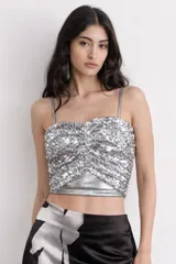 Top de lentejuelas plateadas con frunce en el frente y tirantes finos.
