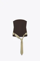 Top palabra de honor color marrón oscuro, con escote recto y hombros descubiertos. Incluye un cinturón en forma de corbata con estampado geométrico en tonos beige y blanco, que se anuda en la parte frontal. Cierre lateral con cremallera oculta.