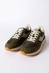 Championes urbanos de diseño técnico, combinando paneles de gamuza y tela en tono verde oliva con detalles en beige y negro. Presentan una suela de plataforma en color crema con base dentada en tono caramelo.