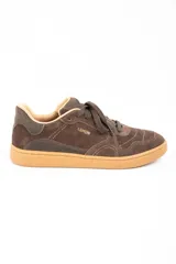 Zapatilla urbana de gamuza color marrón, con cordones al tono, suela de goma color caramelo y logo de la marca grabado en el lateral.