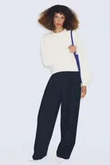 Jersey de punto color azul, con cuello redondo, mangas largas amplias y costuras marcadas en el frente.