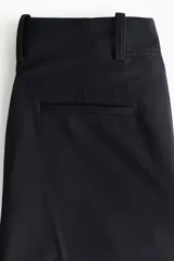 Pantalón sastrero de corte holgado color negro, con cintura clásica, cierre con botón y trabillas para cinturón. Cuenta con piernas rectas, pinzas, bolsillos al bies y raya marcada adelante y atrás.
