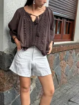 Short de lino en color celeste, con diseño de tiro alto, cierre frontal con botón a la vista y costuras decorativas verticales en el frente.