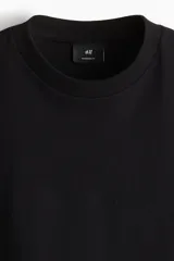 Remera de manga larga en punto pesado, color negro, con cuello redondo ribeteado, hombros caídos y bajo recto. Corte oversized para una silueta amplia y relajada.