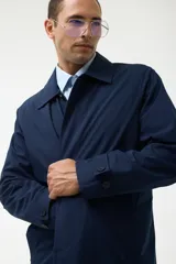Gabardina azul marino con cuello clásico, cierre frontal con botones y bolsillos laterales.