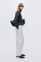 Pantalón sastrero de tiro alto con pinzas, corte holgado y piernas rectas. Presenta cierre frontal con botón y corchete ocultos, bolsillos laterales discretos y bolsillos traseros decorativos.