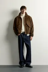 Cazadora de hombre regular fit confeccionada en tejido efecto ante, con acabado lavado, cuello solapa, manga larga, bolsillos de plastrón con solapa en la cadera, detalles elásticos en puños y cintura, y cierre frontal de cremallera.