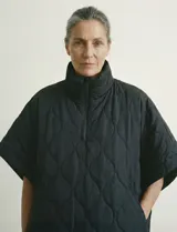 Poncho acolchado color vino tinto, con cuello alto y cierre frontal parcial. Presenta un patrón de costuras capitoné en forma de hoja o diamante y bolsillos delanteros.