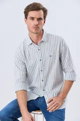 Camisa de manga larga de lino y algodón, con diseño de rayas verticales en tonos celestes y blancos. Presenta cuello camisero, cierre frontal con botones y pequeño bordado al tono en el pecho.