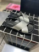 Sandalias chatas plateadas con tiras cruzadas y base cuadrada negra.