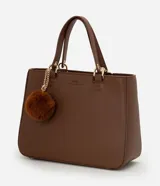 Cartera estilo satchel de tamaño mediano, confeccionada en poliuretano color marrón con textura tipo cuero. Cuenta con asas de mano reforzadas, correa larga desmontable, cierre superior de cremallera y un colgante decorativo de pompón de pelo sintético.
