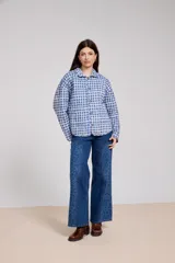 Jean de corte recto y tiro alto, confeccionado en denim azul. Presenta paneles laterales con estampado floral sutil en un tono más oscuro, costuras visibles y cierre frontal con botón.