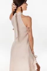 Vestido midi marrón de lino italiano, con cuello halter, sin mangas y diseño asimétrico con volados en el ruedo.
