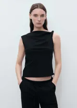 Top sin mangas de color negro con cuello asimétrico y detalle drapeado en el escote. Presenta un diseño recto y cierre de cremallera lateral.