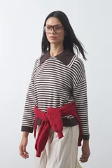 Sweater de punto a rayas horizontales en color bordó y celeste, con cuello polo y mangas largas con puños amplios. Presenta un diseño de calce relajado.